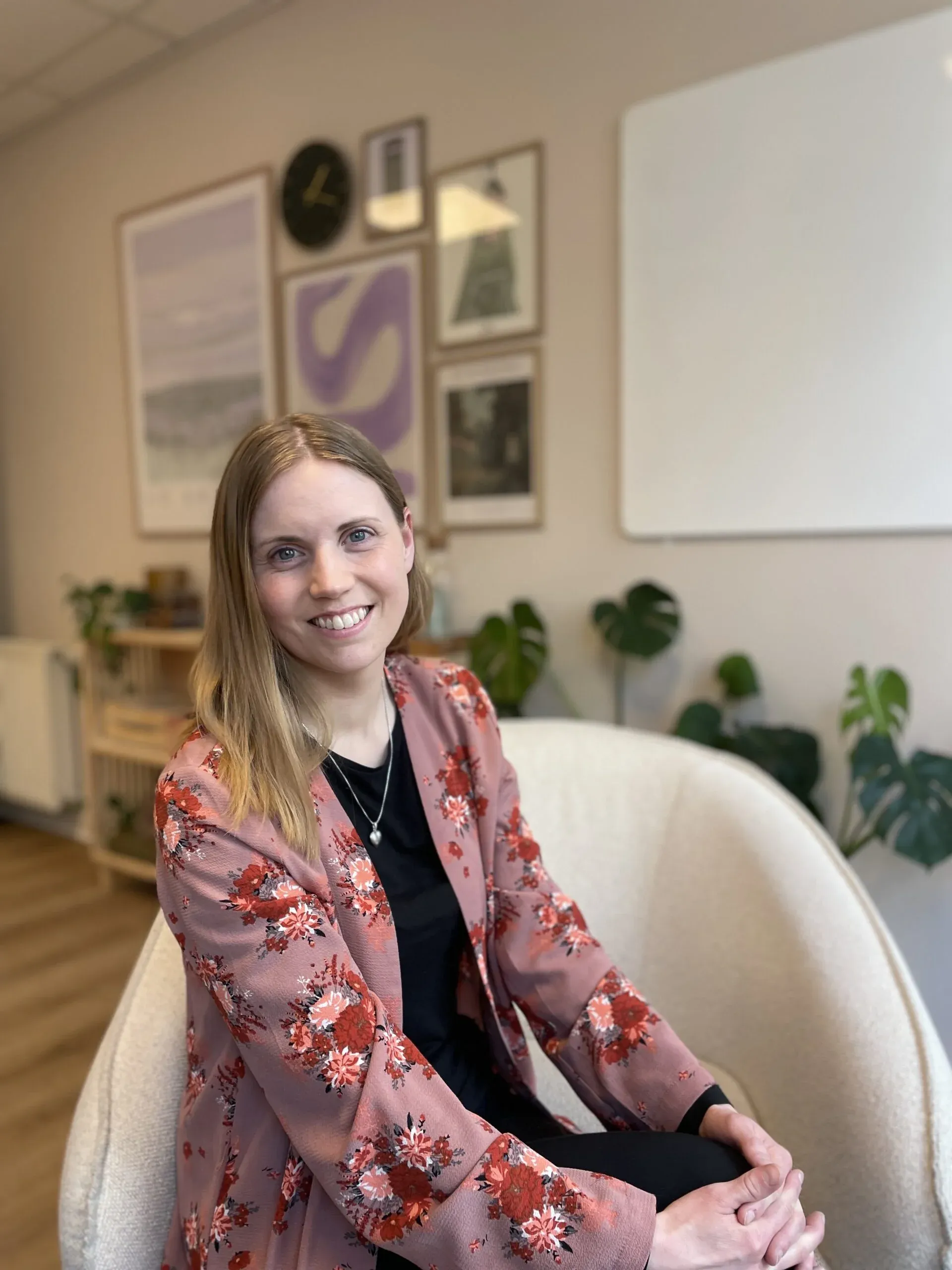 Kvinde sidder smilende i moderne kontormiljø